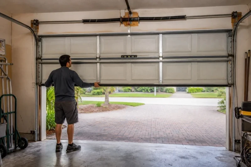 Person holding the lower edge of a partly raised sectional garage door